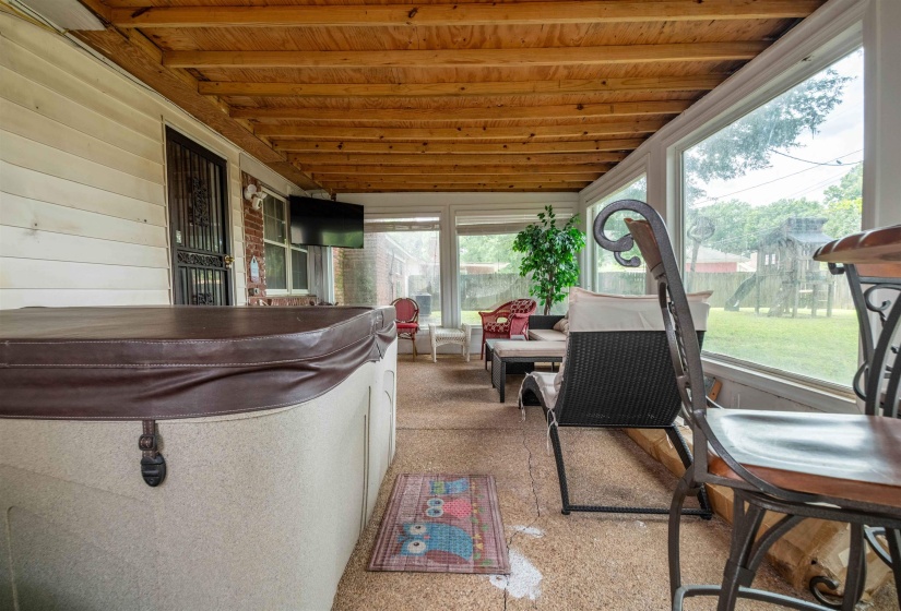 Sunroom with a wood-finish ceiling, large windows, and a built-in television mount