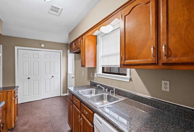 Kitchen featuring a double basin stainless steel sink, dark speckled countertops, and wood cabinetry