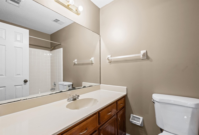 Bathroom featuring a vanity with a light-colored countertop, wood-finish cabinetry, and a mirrored wall