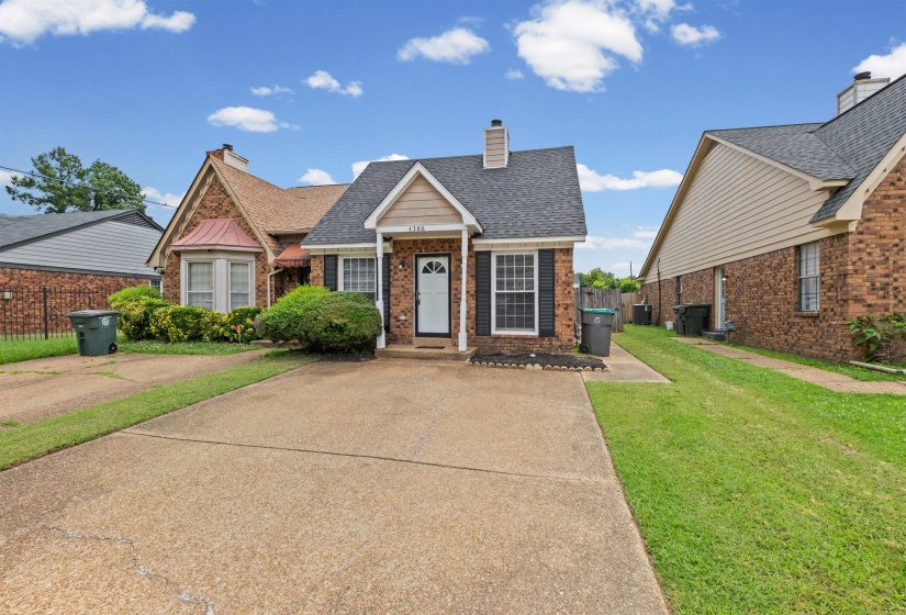 Brick exterior with a prominent front entry porch, a large concrete driveway, and a manicured front lawn