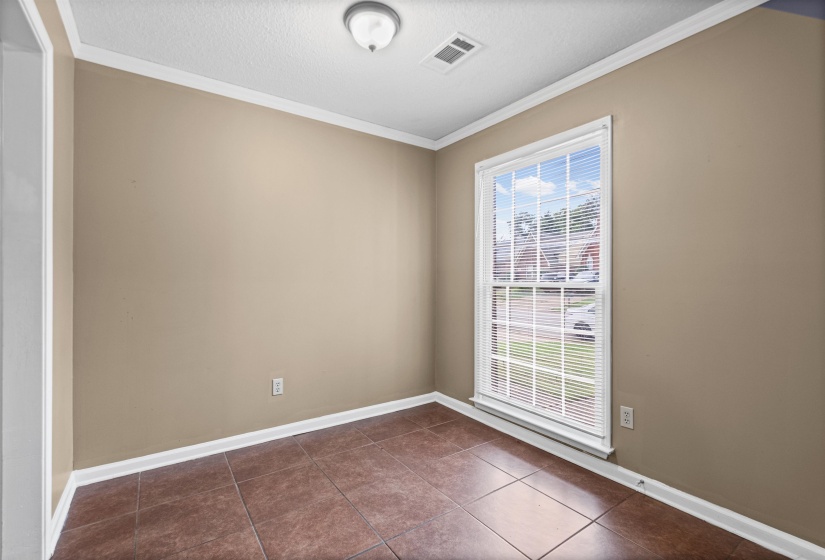 Room featuring a large window, brown tile flooring, and neutral-toned walls with white trim