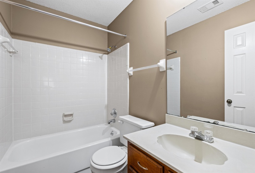 Full bathroom featuring a white tub, shower with white tiled surround, and a vanity with an integrated sink