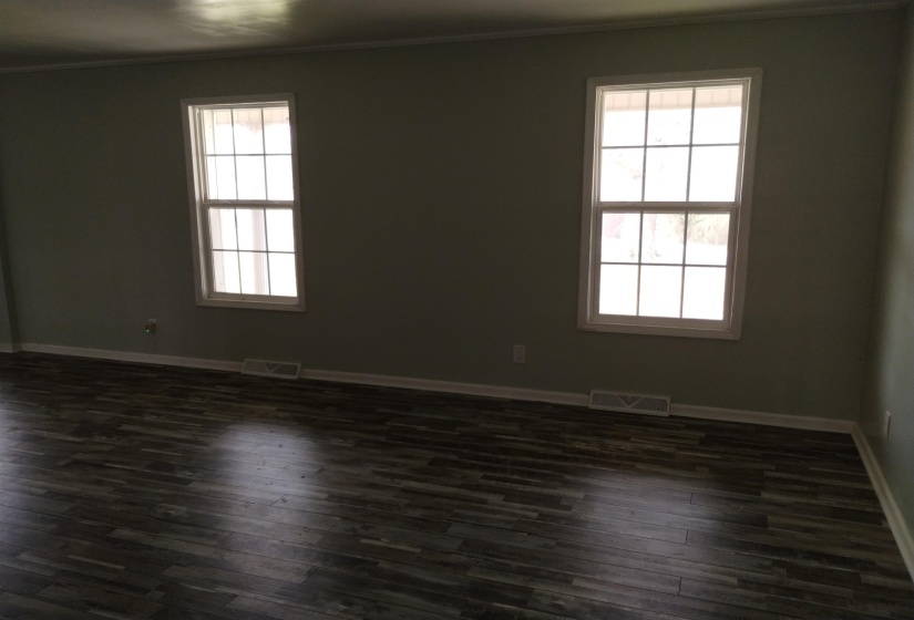 Interior room featuring two multi-pane windows with white trim, light gray walls, white baseboards, and wood-finish flooring