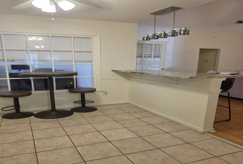 Tiled flooring extending from a breakfast bar with a light-colored countertop