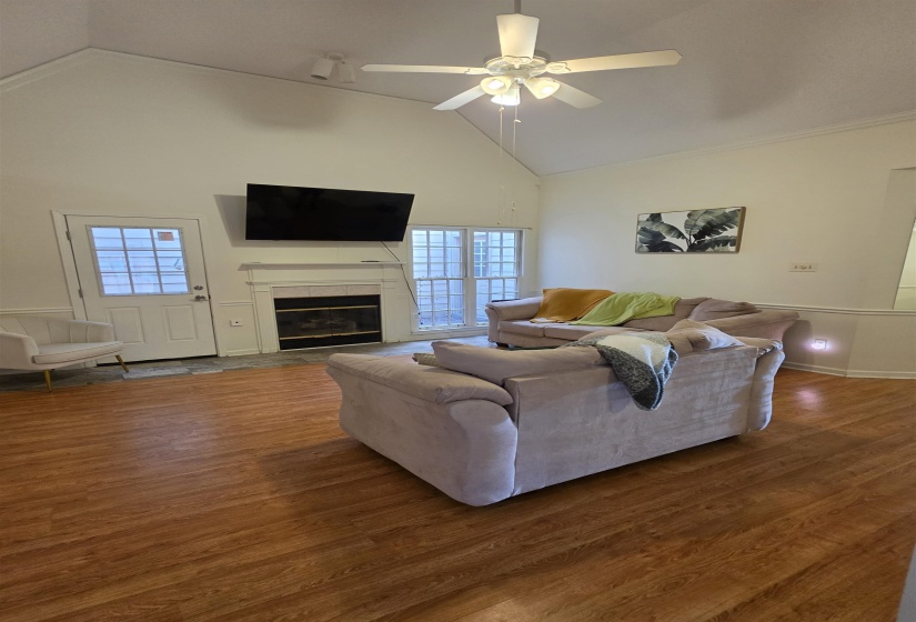 Spacious living area featuring a vaulted ceiling and wood-finish flooring