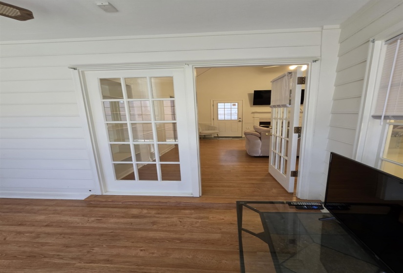 French doors with multi-pane glass panels, wood-finish flooring, and white horizontal wall paneling