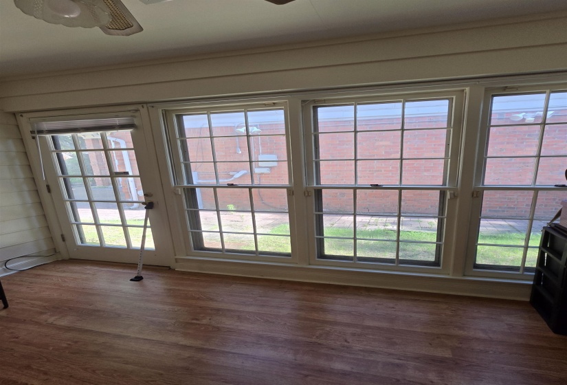 Sunroom featuring a full-light glass-paned door, three large glass-paned windows, wood-finish flooring, and white trim