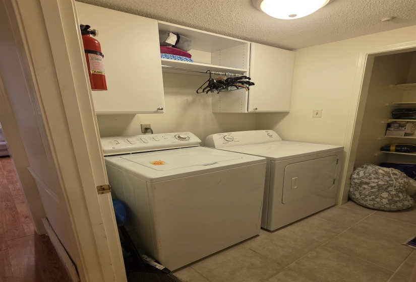 Dedicated laundry area featuring a white washer and dryer, overhead white cabinetry, and a ceiling-mounted light fixture