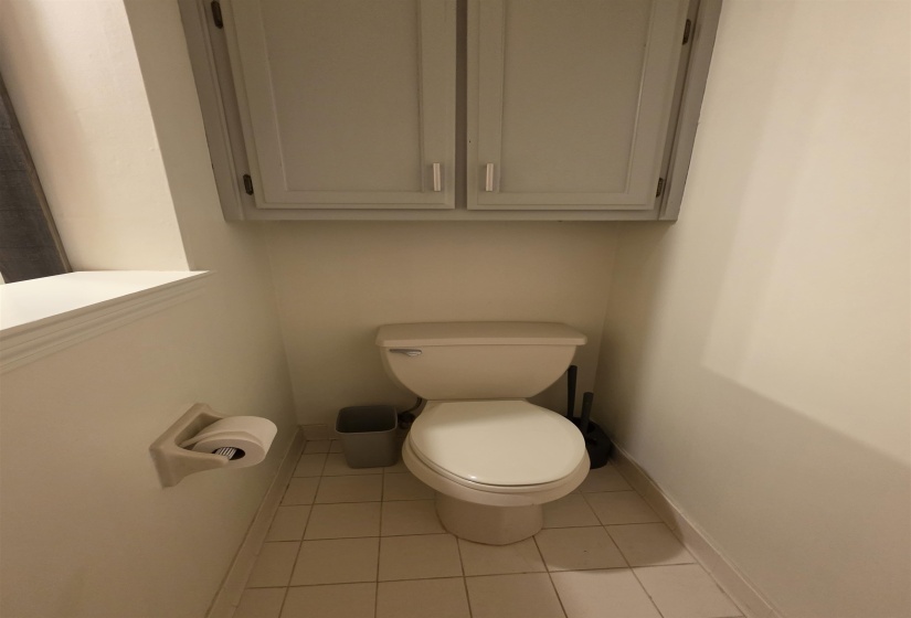 Recessed toilet area featuring overhead cabinetry