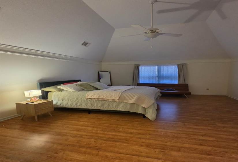 Vaulted ceiling with a ceiling fan, crown molding, a window with blinds and curtains, and wood-finish flooring
