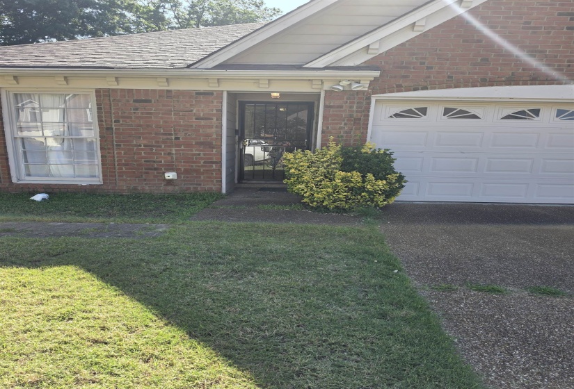 Brick exterior with a gabled roofline, featuring a white garage door with decorative arch window inserts