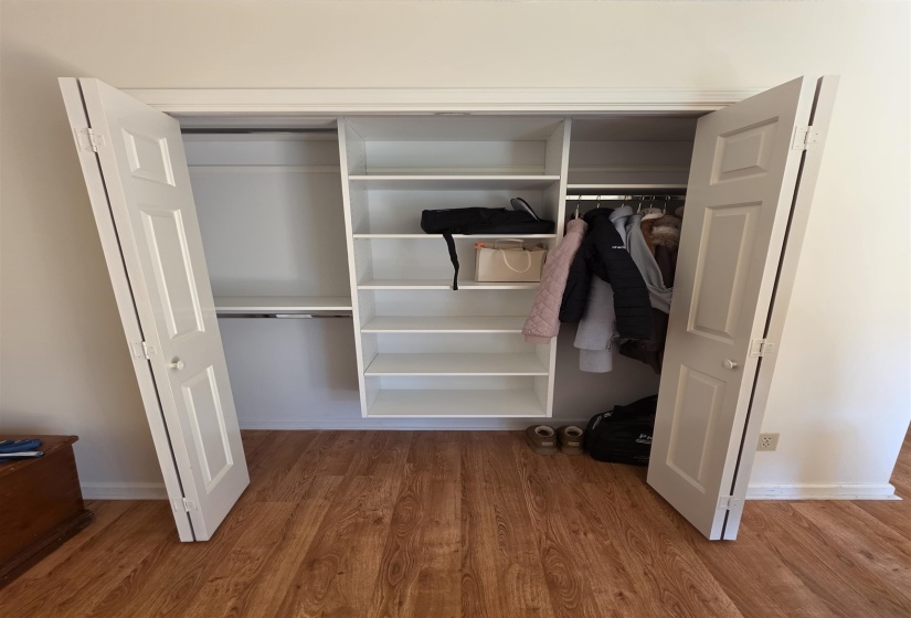 Integrated closet system featuring white bi-fold doors, multiple hanging rods, and central shelving