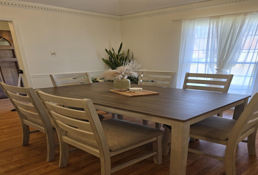 Hardwood-finish flooring grounds this space, featuring white crown molding and wall trim