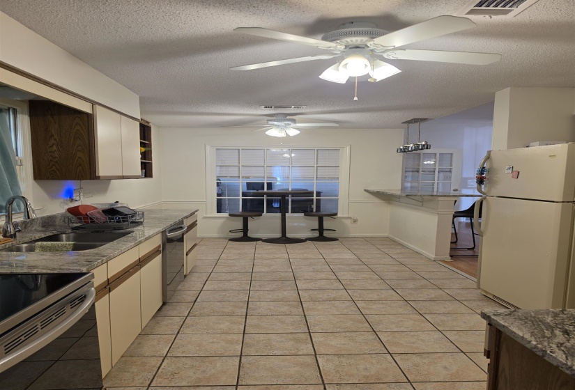 Spacious kitchen featuring tile flooring, granite countertops, and light cabinetry