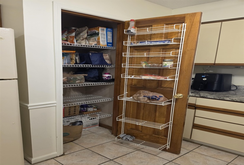 Kitchen pantry featuring wire shelving, a natural wood-finish door, and additional door-mounted storage