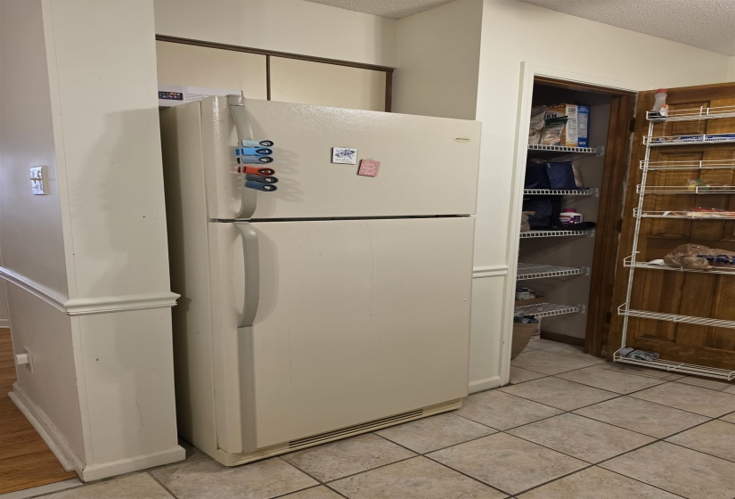 Kitchen area featuring neutral-toned tile flooring and a pantry with wire shelving