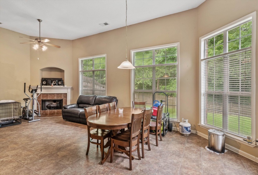 Open-concept living space featuring high ceilings, a tiled fireplace with a mantel, and large windows with blinds