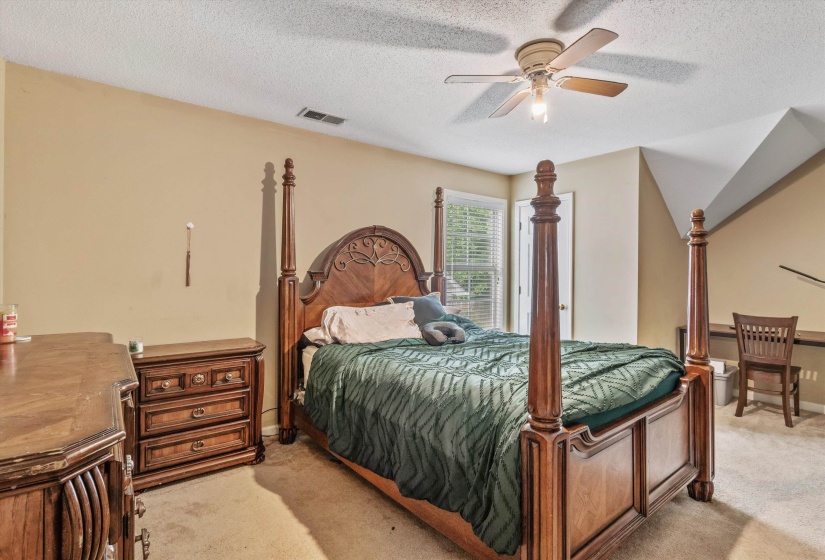 Carpeted bedroom featuring a sloped ceiling and a ceiling fan with light fixture