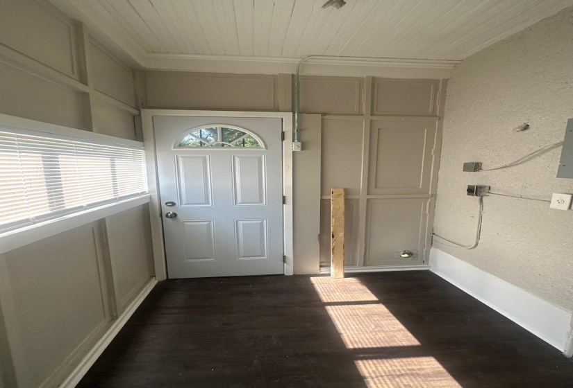 Entryway featuring a white paneled door with an arched glass insert, dark wood-finish flooring, and light-colored wainscoting