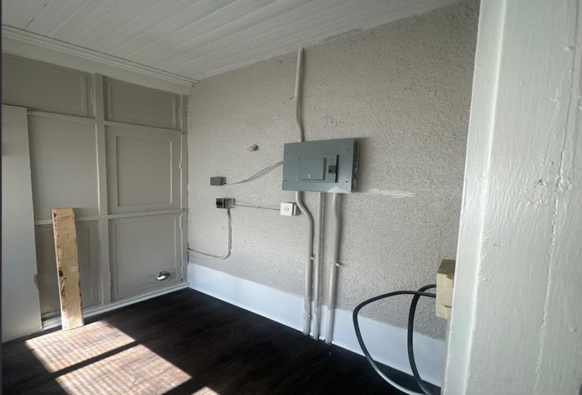 Utility area featuring a visible electrical panel, dark wood-finish flooring, and white beadboard ceiling