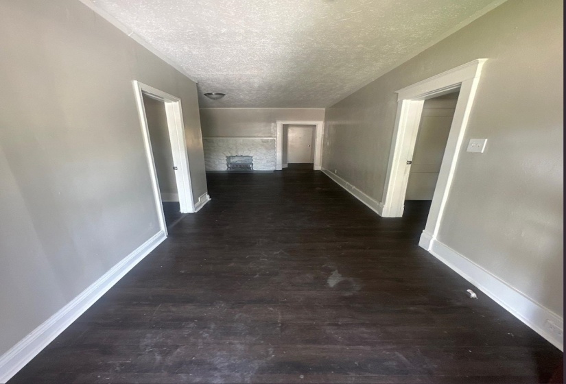 Interior hallway featuring wood-finish flooring, light gray wall paint, white trim, and doors leading to other rooms
