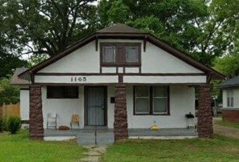 White exterior with dark trim and stone pillars framing the front porch