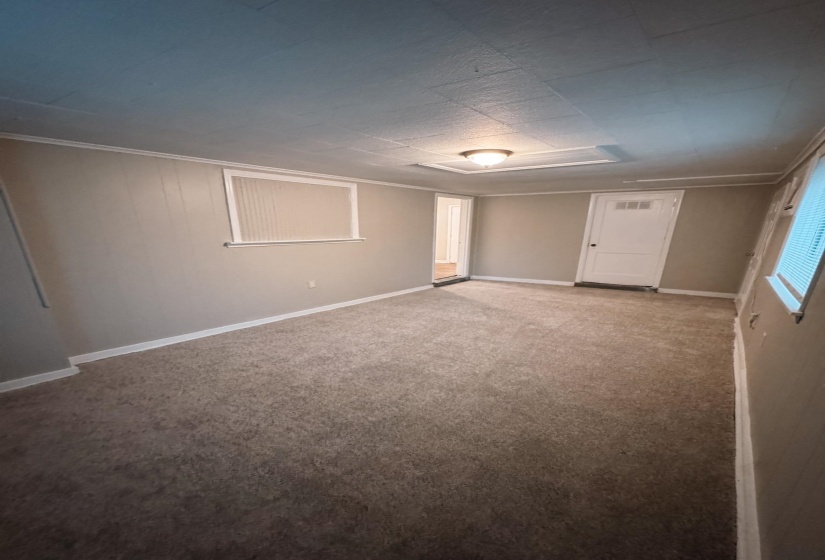 Spacious room featuring neutral carpeting, light gray wall paint, white trim, and a flush-mount ceiling light fixture