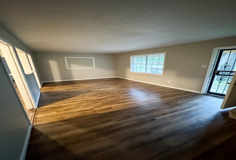 Spacious room featuring wood-finish flooring, neutral wall paint, and white trim throughout