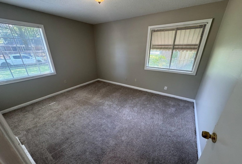 Carpeted room featuring two windows with horizontal blinds, light tan wall paint, and white trim