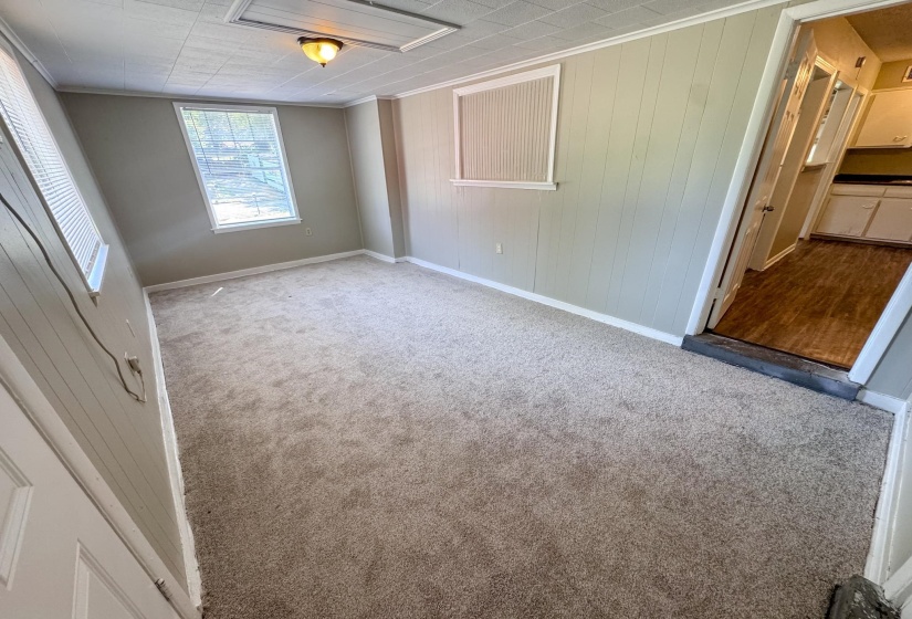 Carpeted room featuring a light fixture, baseboards, window, and plank-style wall paneling
