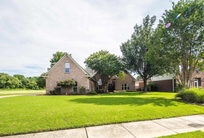 Brick exterior residence featuring a gabled roofline and mature trees