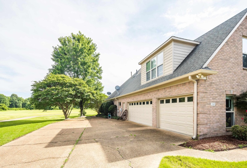 Brick exterior featuring a two-car garage with individual doors, a dormer window, and mature landscaping