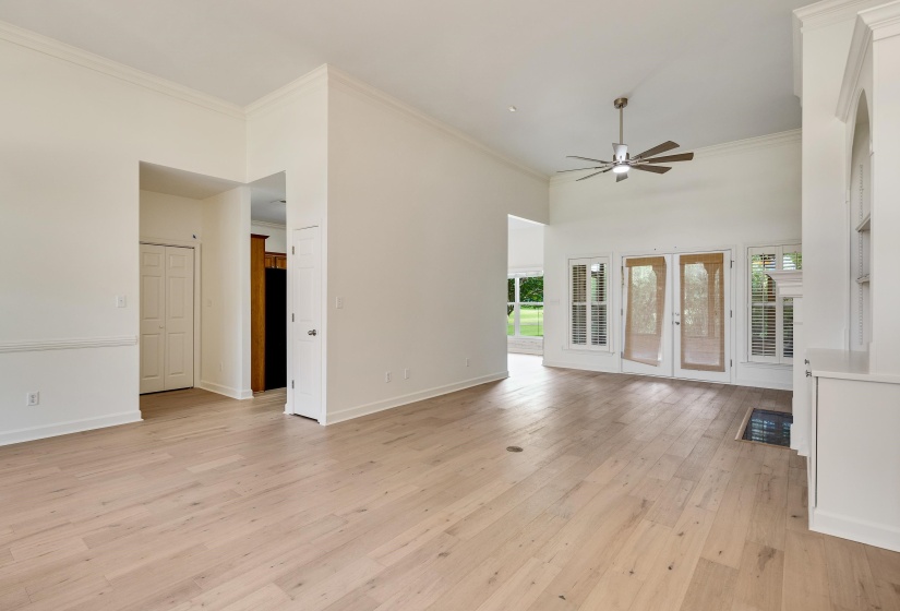 Spacious living area featuring light wood-finish flooring, vaulted ceilings, and crown molding