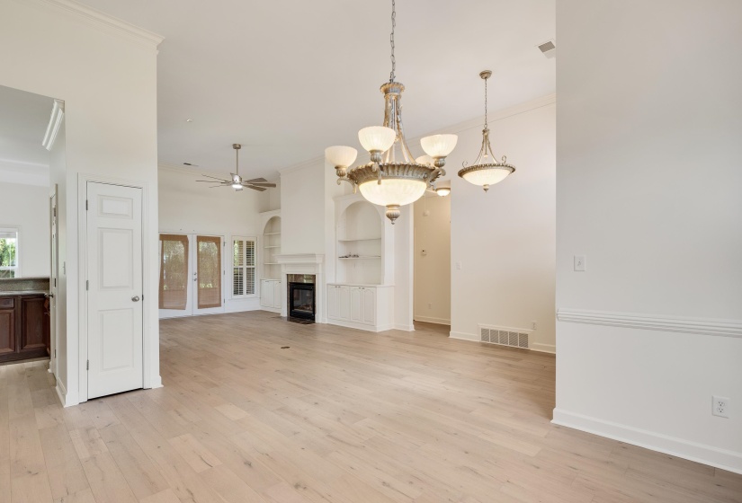 Expansive living area with light wood-finish flooring, vaulted ceilings, and crown molding