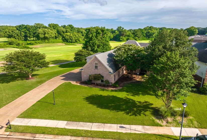 Brick exterior residence featuring a gray shingle roof and a verdant golf course backdrop
