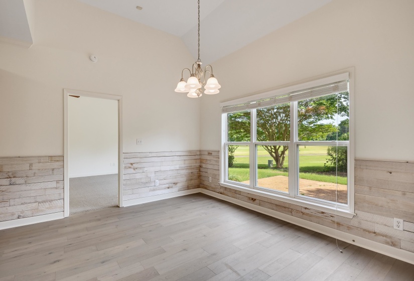Versatile interior space featuring wood-finish flooring, shiplap wainscoting, and a prominent window