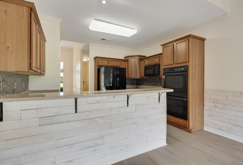 Kitchen featuring light wood cabinetry, a built-in double oven, and black appliances