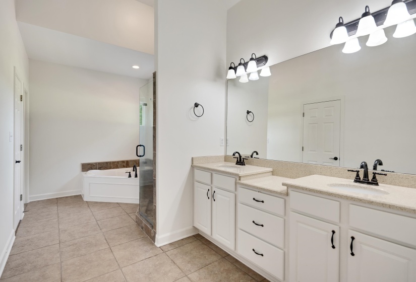 Bathroom featuring a dual vanity with light-colored countertops, white cabinetry, and matte black fixtures