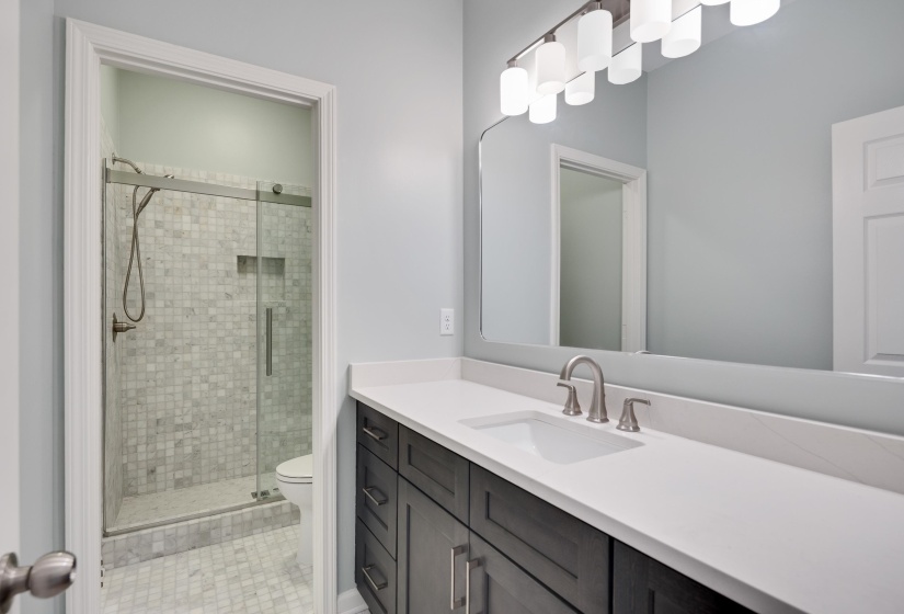 Bathroom featuring a dark wood vanity with a white countertop and undermount sink, brushed nickel faucet, and a large mirror with a multi-bulb light fixture