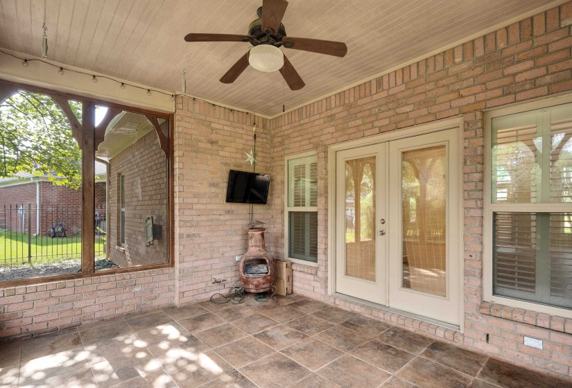 Covered patio featuring brick walls, a wood-finish ceiling with a ceiling fan, and large format tile flooring