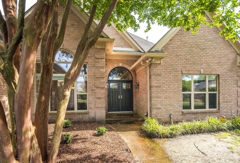 Brick exterior featuring an arched entryway with double doors, arched transom window, and a gabled roofline