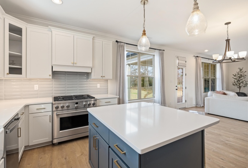 Two tone kitchen with dual tone cabinets, stainless steel appliances, ornamental molding, open floor plan, and tasteful backsplash