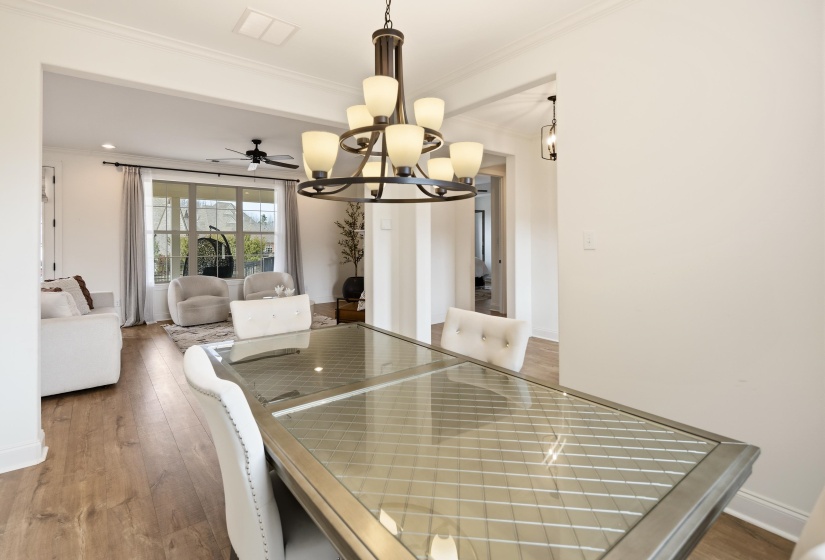 Dining space with light wood-type flooring, ceiling fan, ornamental molding, and suspended lighting