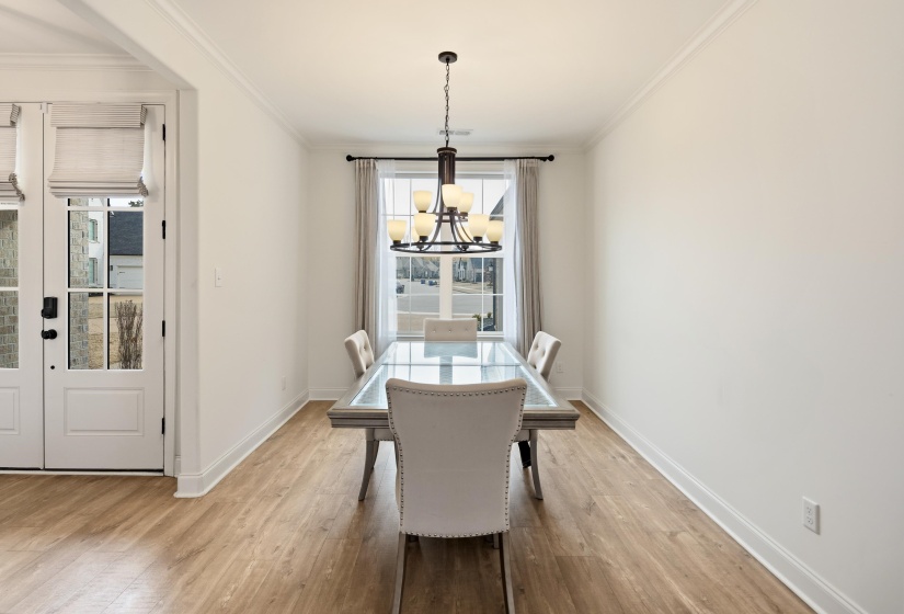 Dining space with crown molding, light wood-style flooring, and suspended lighting
