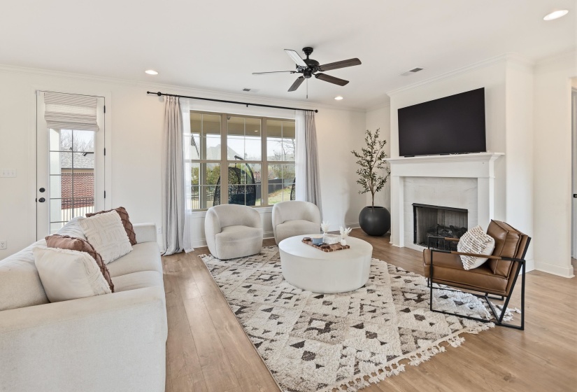 Living area with light wood-type flooring, plenty of natural light, ceiling fan, a fireplace, and ornamental molding