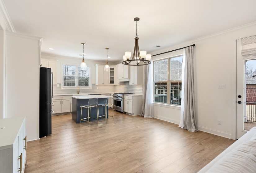 Kitchen with high end range, freestanding refrigerator, glass insert cabinets, a kitchen bar, and light wood-style floors