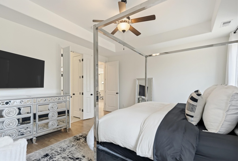Bedroom with wood finished floors, a ceiling fan, and a raised ceiling