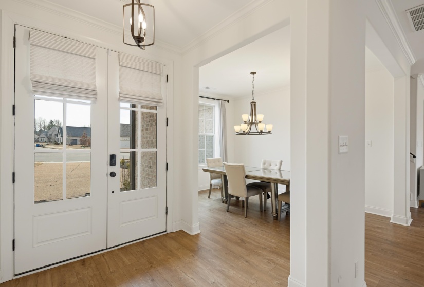 Entryway featuring hanging lights, crown molding, and light wood-type flooring