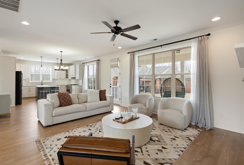 Living room featuring ceiling fan, wood finished floors, crown molding, and hanging lights