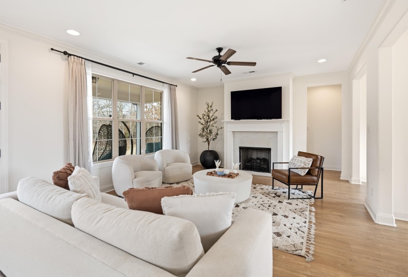 Living room with a ceiling fan, light wood-style floors, a fireplace, crown molding, and recessed lighting